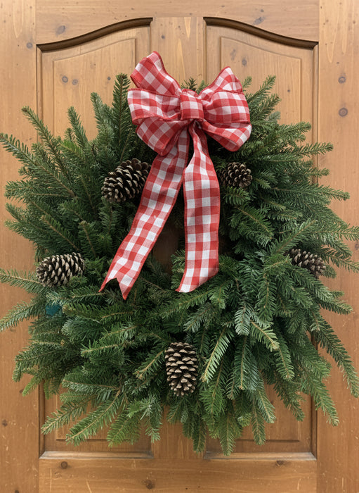 Christmas wreath with a red and white checkered bow on a wooden door